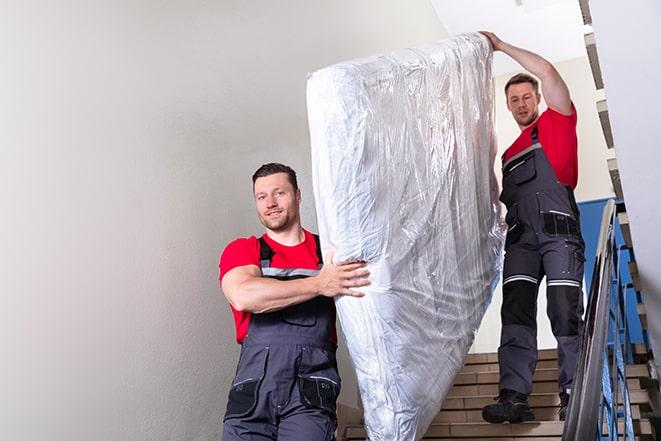 workers maneuvering a box spring through a narrow hallway in El Cajon, CA