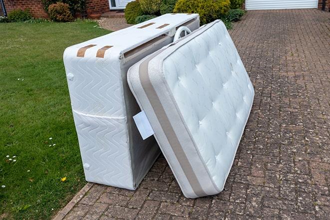 men carefully carrying a dirty mattress out of a building